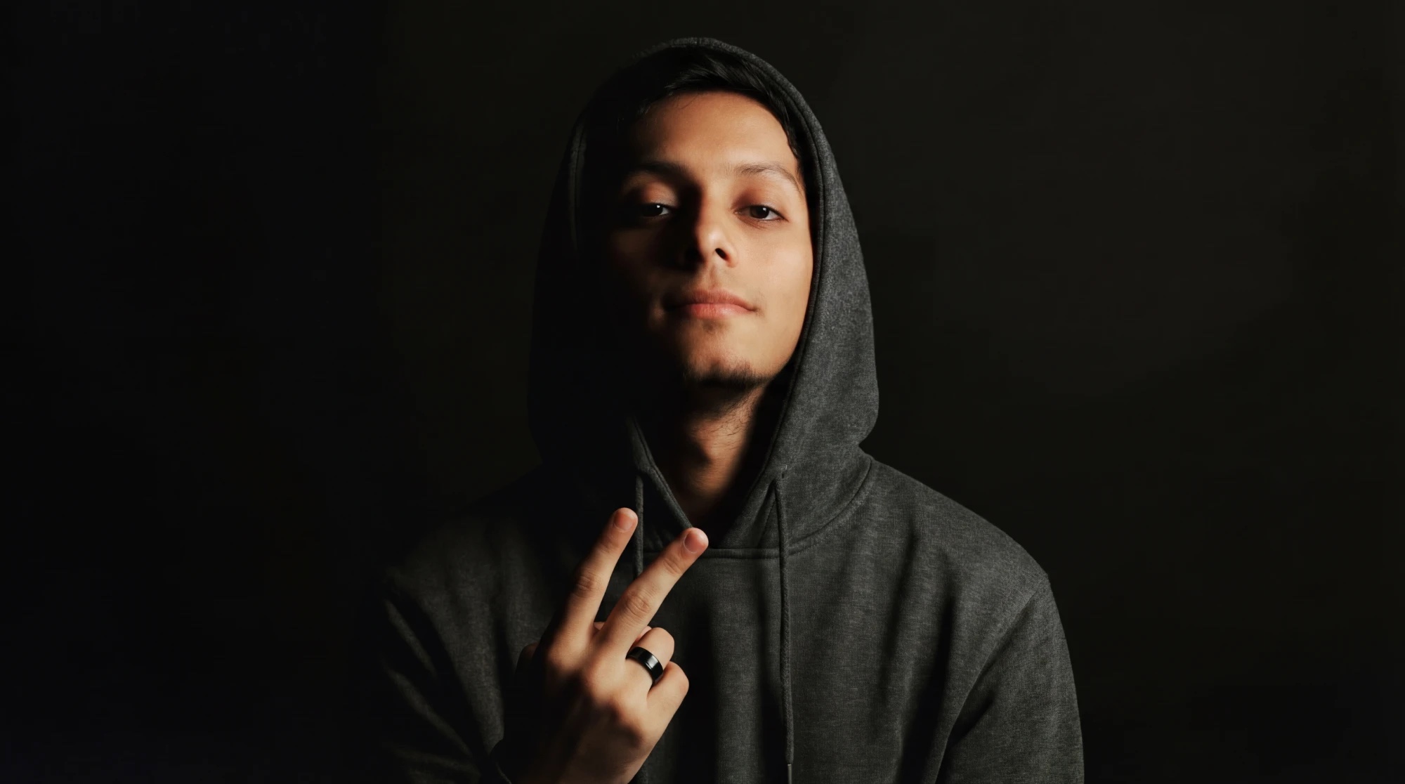 Portrait of Yash Vijay in a grey hoodie against a black background